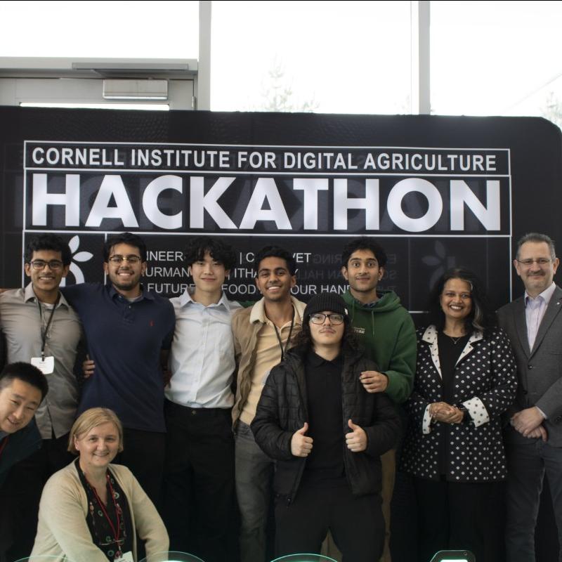 Several people pose in front of a sign that says "HACKATHON"
