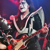 Person wearing white and black makeup and a silver and black costume, playing an electric guitar
