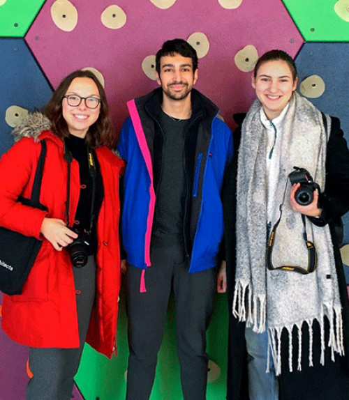  Three students holding camaras, colorful background